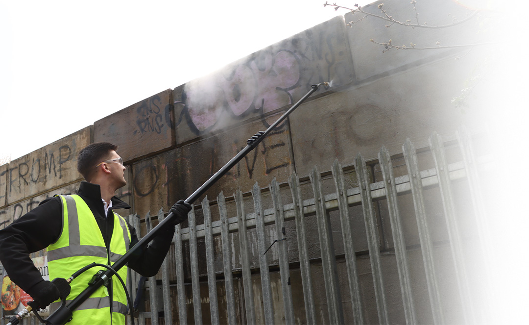 Man cleaning Graffiti with a high pressure washing pole