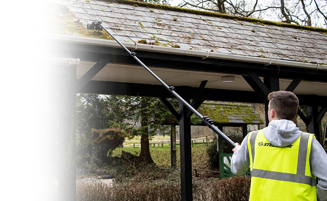 Man clearing moss from roof using water fed pole moss removal attachments