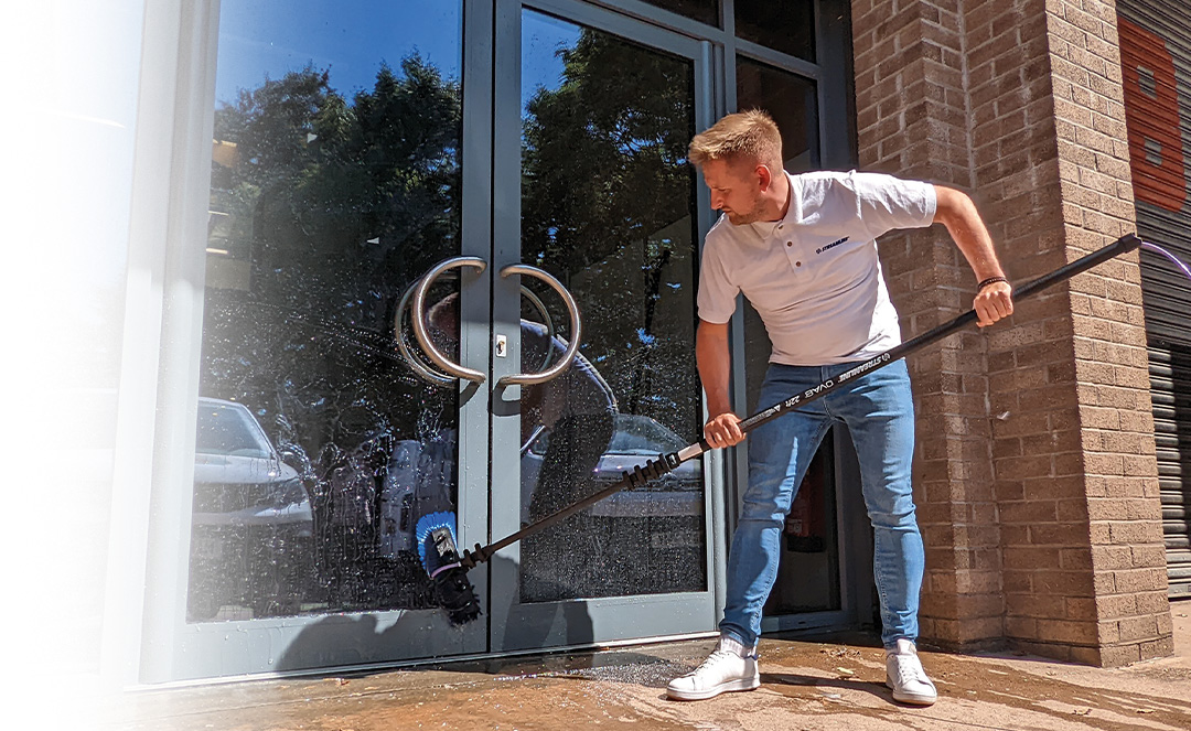 Man cleaning a glass door with an OVA8 telescopic window cleaning pole
